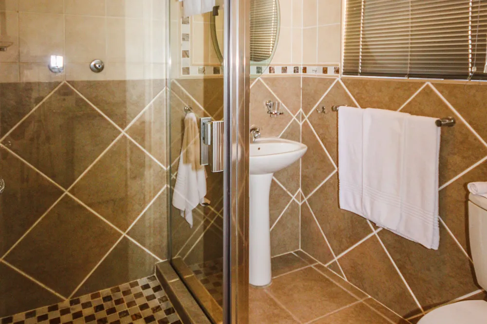 Modern bathroom with a glass shower sink toilet and tiled walls