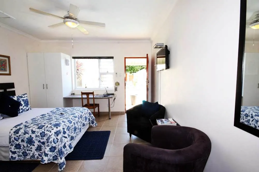 Cozy bedroom with a bed desk chair and open door to outside