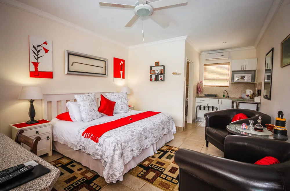 Cozy bedroom with a bed seating area and kitchenette decorated in red and white