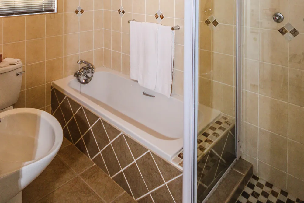 Beige bathroom with bathtub bidet and tiled walls and floor