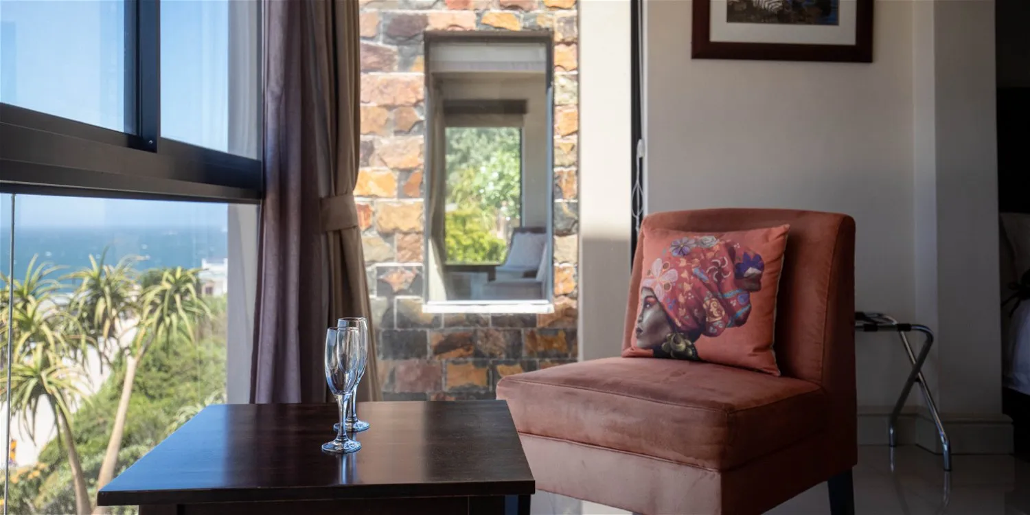 Cozy room with armchair table and large window overlooking palm trees and ocean