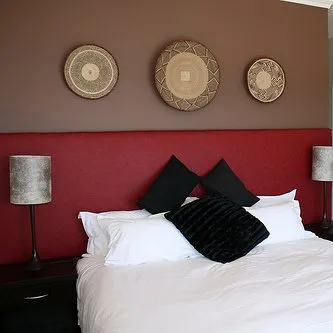 Red headboard white bed black pillows wall art bedside lamps in a bedroom