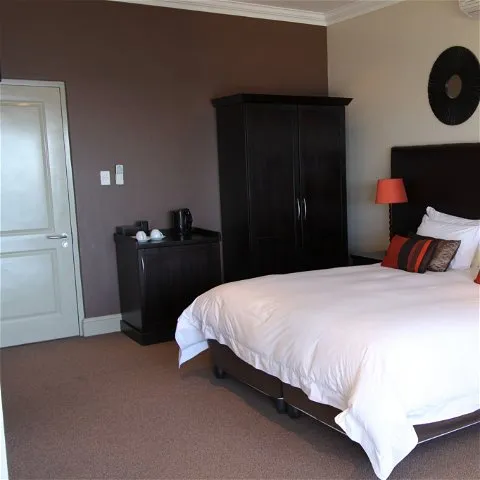 Bedroom with a large bed wooden wardrobe and dark brown walls