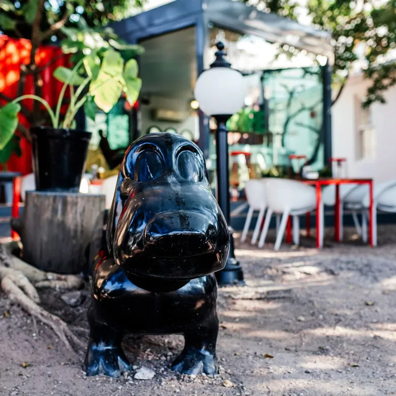 Black hippo statue in a garden with outdoor seating and plants