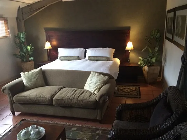 Bedroom with a large bed sofa armchair and bedside lamps with plants