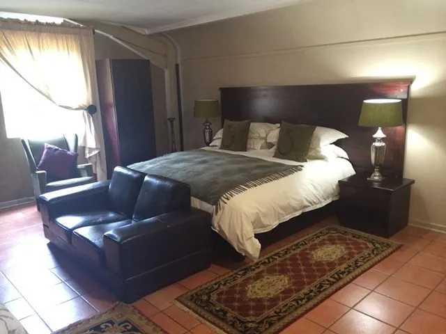 Bedroom with a large bed sofa and bedside lamps on a tiled floor