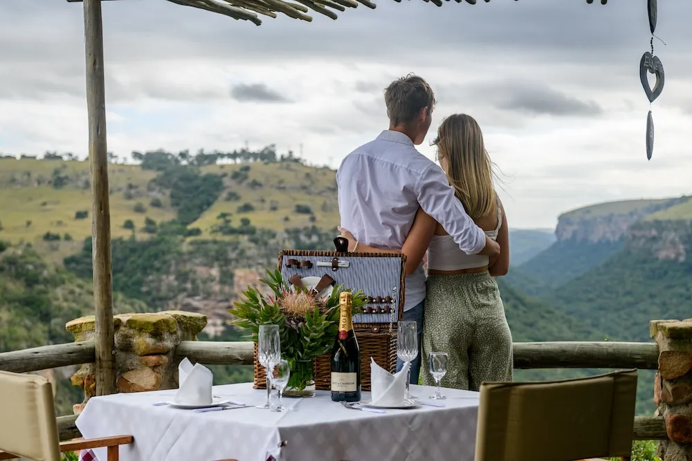 Couple embracing at a romantic outdoor picnic table with scenic valley view