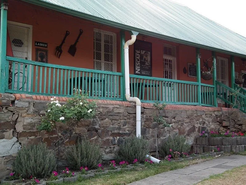 A colorful building with a green roof garden and kitchen utensils on the wall