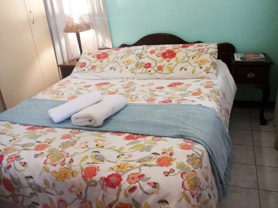 Floralpatterned bed with white towels and a blue throw in a bedroom