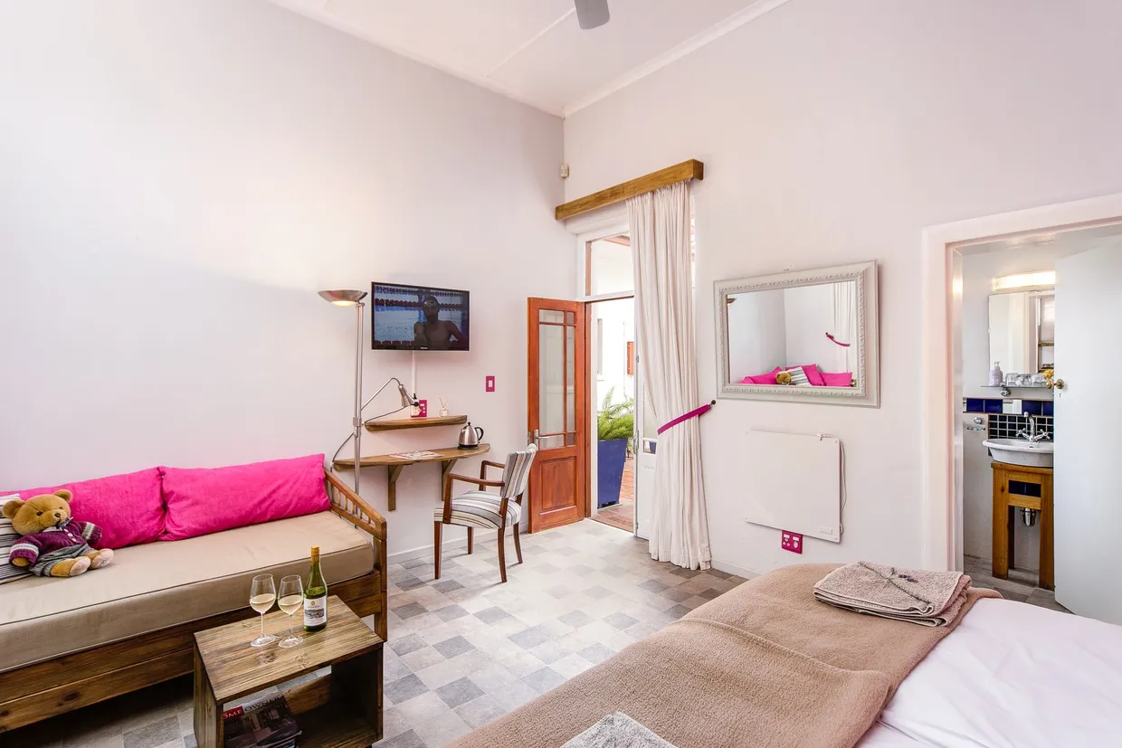 Cozy bedroom with a bed sofa desk TV and a bathroom entrance