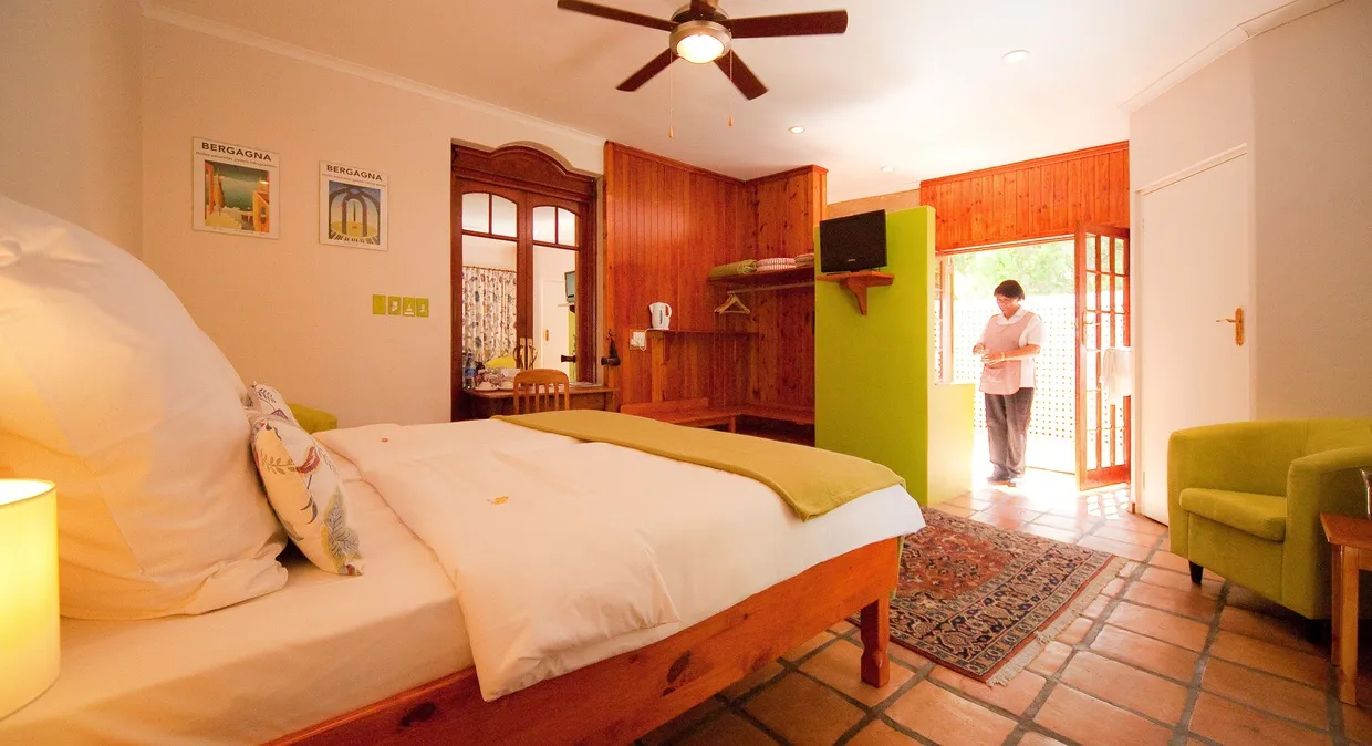 Cozy bedroom with wooden furniture open door to garden and ceiling fan