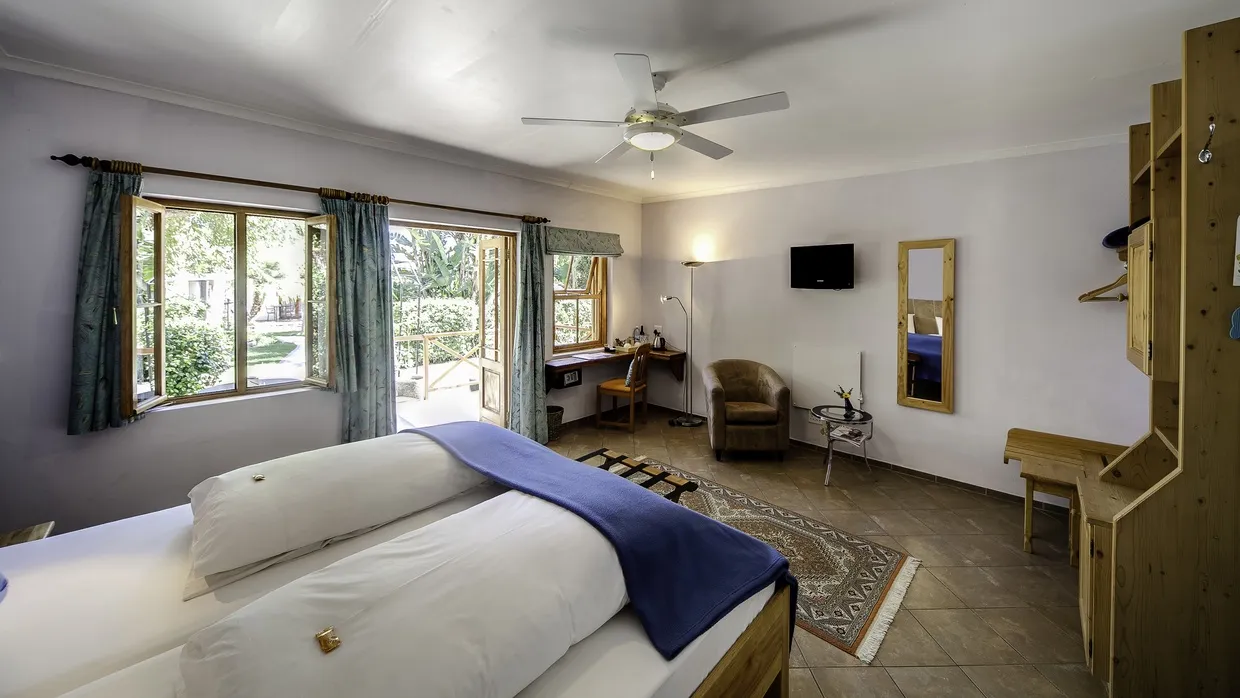 Cozy bedroom with a bed desk chair and ceiling fan open window view