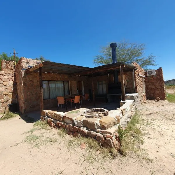 Stone house with outdoor seating and a fire pit under a clear sky