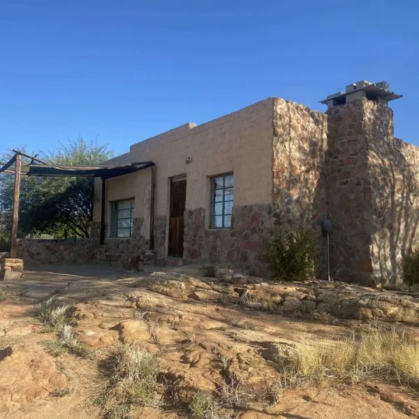 Adobestyle house with stone chimney in a desert landscape under clear blue sky