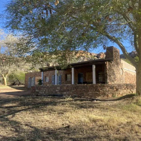 Stone house with porch and trees in a dry sunny landscape