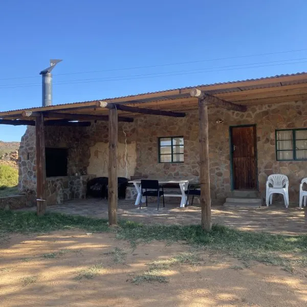 Stone cabin with wooden porch table chairs and clear blue sky