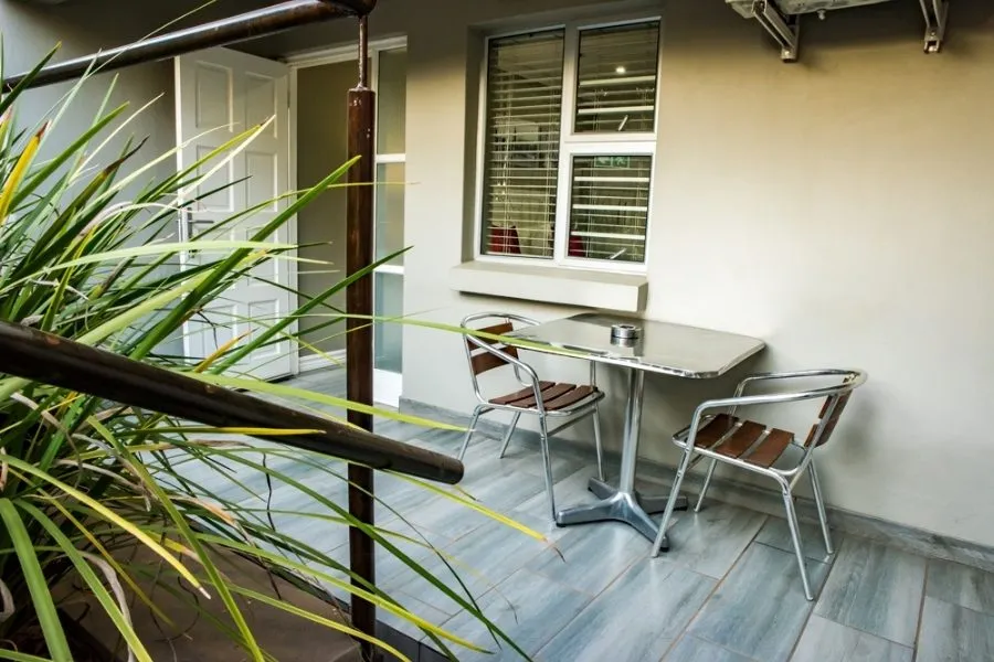 Balcony with table chairs and potted plant near a window and door