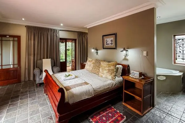 Bedroom with wooden sleigh bed bedside table and adjacent bathroom with tub
