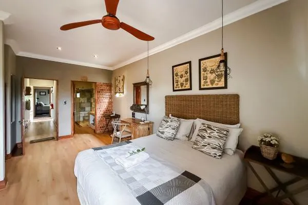 Bedroom with wooden floor ceiling fan wicker headboard and artwork on walls