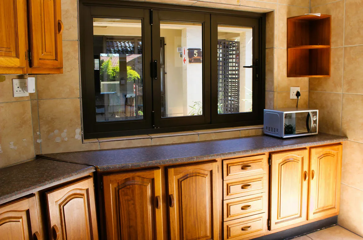 Kitchen with wooden cabinets microwave and a window with a view outside