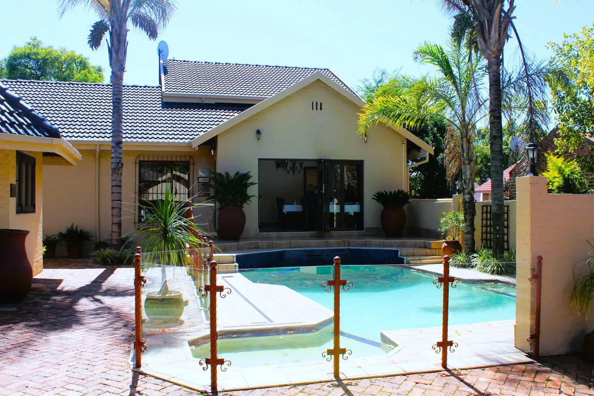 House with a swimming pool and palm trees in a sunny garden