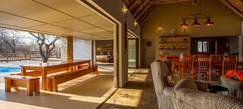 Openplan living area with wooden furniture large windows and outdoor view