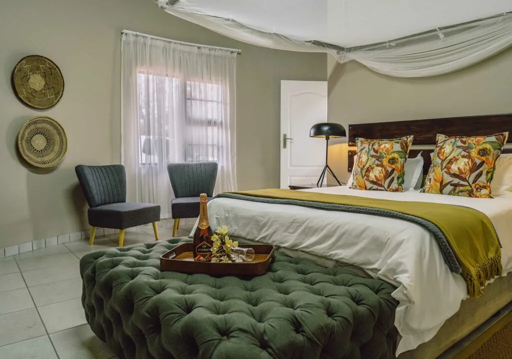 Cozy bedroom with large bed green ottoman and two chairs near window