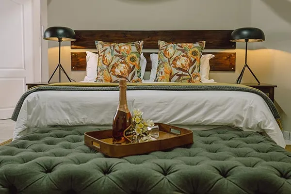 Bedroom with large bed patterned pillows and a bottle on a tray