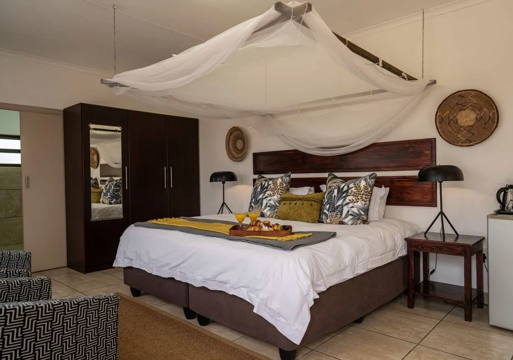 Bedroom with large bed canopy and bedside lamps decorated with African motifs