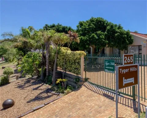 House with garden palm trees and sign for Tyger Hills accommodation