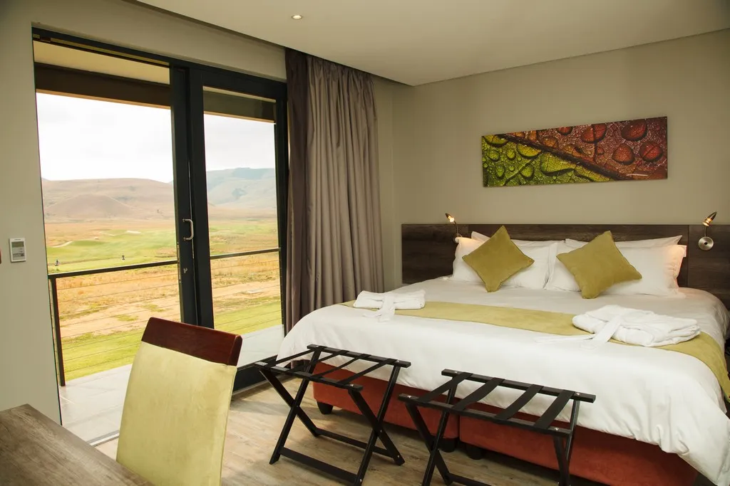 Modern bedroom with large bed colorful artwork and scenic view through glass doors