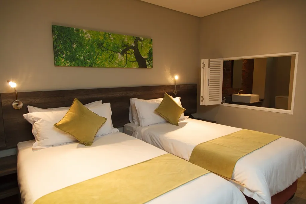 Two single beds with yellow cushions in a modern bedroom with wall art