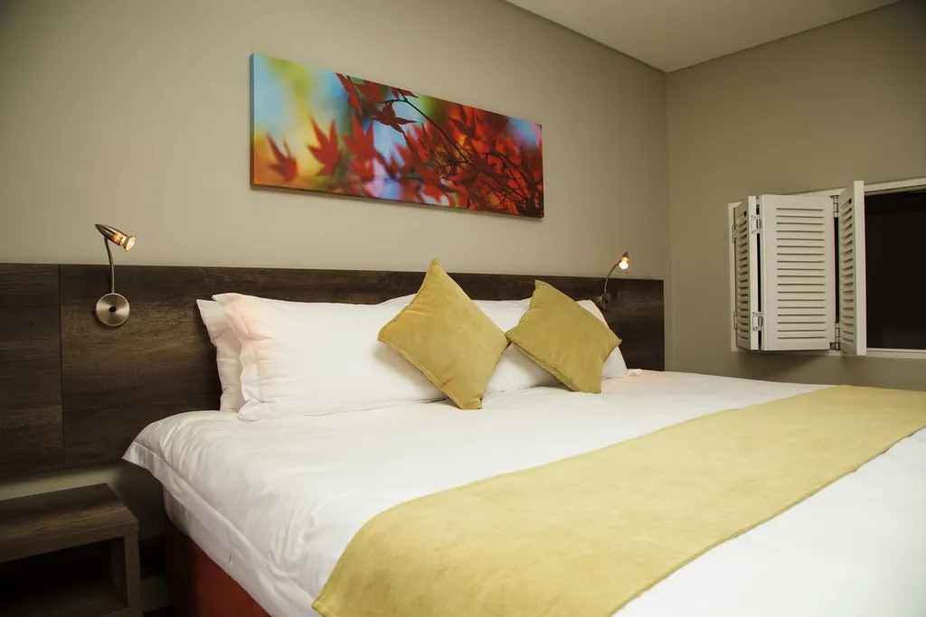 Modern bedroom with a large bed colorful pillows and a vibrant wall art