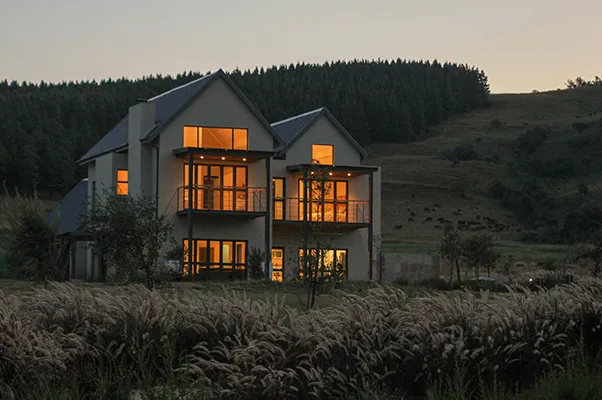 Modern house with lit windows in a rural setting at dusk