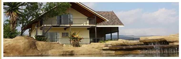 Yellow house with balcony overlooking a rocky waterfall and pond surrounded by greenery