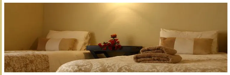 Two beds in a cozy bedroom with folded towels and flowers on a table
