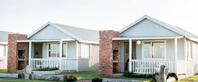 Two small houses with verandas in a grassy area