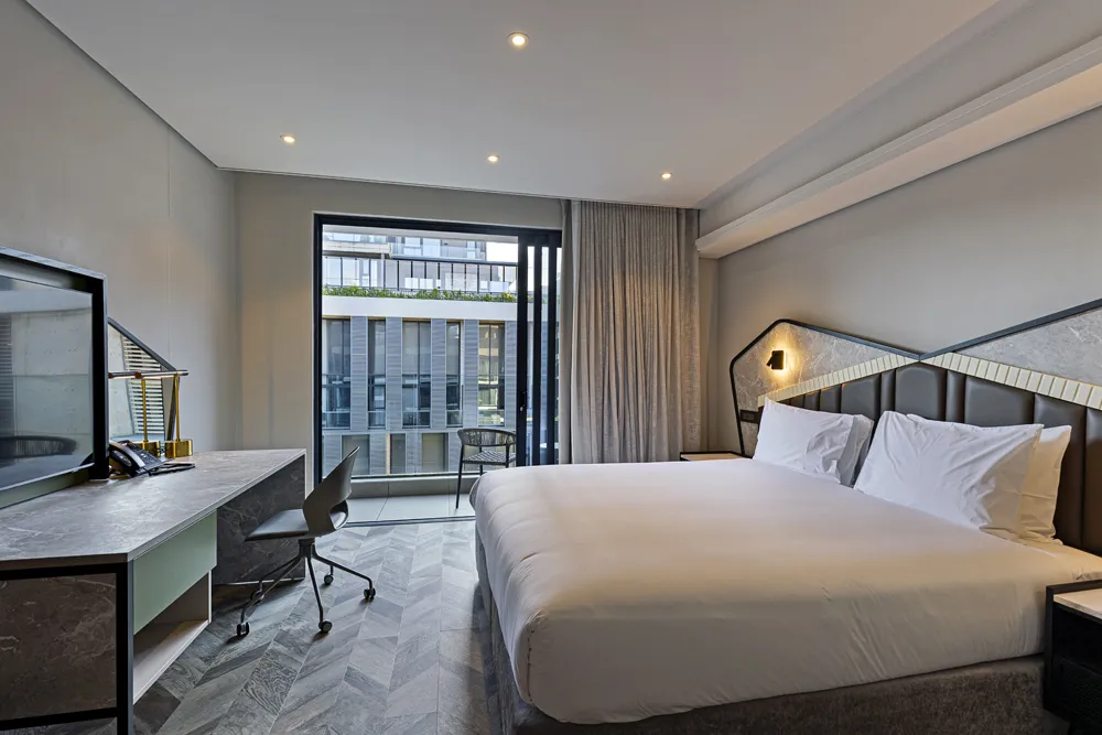 Modern hotel room with large bed desk and city view through large windows