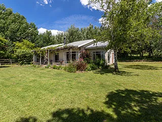 Singlestory house with a garden surrounded by trees on a sunny day