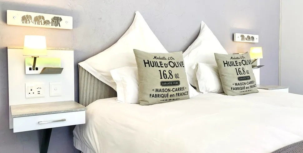 Bed with white linens decorative pillows and bedside shelves with lamps and outlets