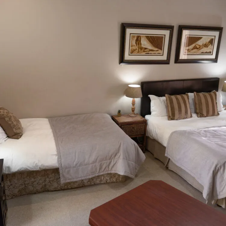 Hotel room with two beds bedside tables lamps and framed artwork on the wall