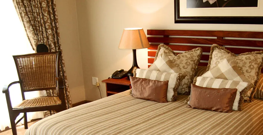 Cozy bedroom with neatly made bed bedside table lamp and wicker chair