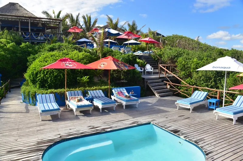 Beach resort with lounge chairs umbrellas and a small pool on a wooden deck