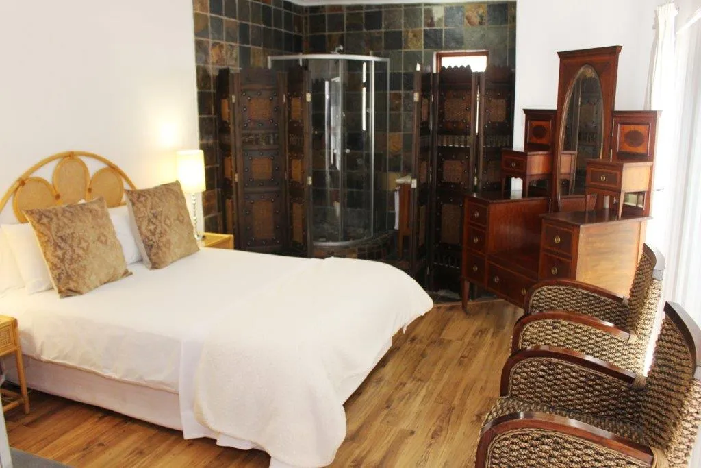 Bedroom with a large bed wooden furniture and a glass shower enclosure
