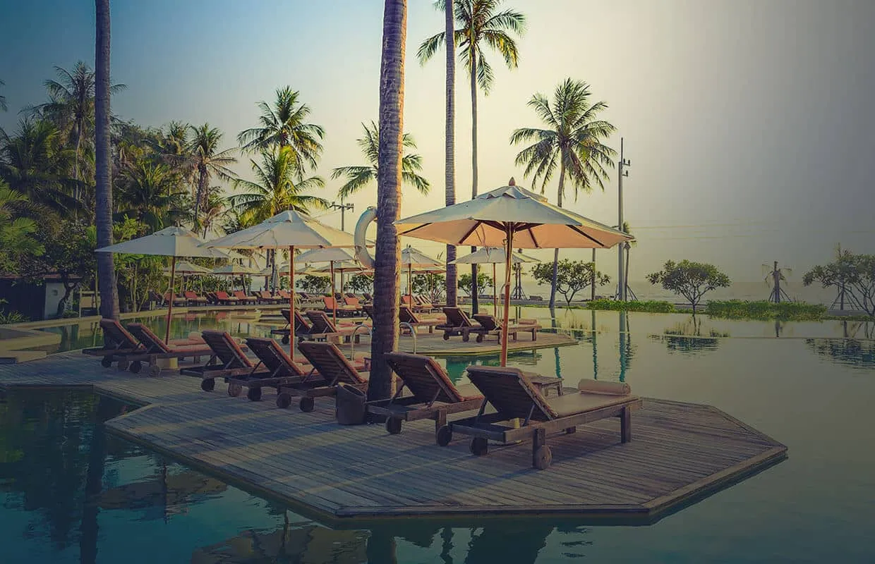 Tropical resort with lounge chairs umbrellas and palm trees by a pool