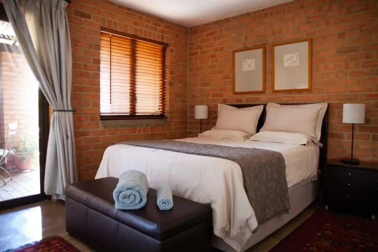 Cozy bedroom with brick walls large bed and window with wooden blinds