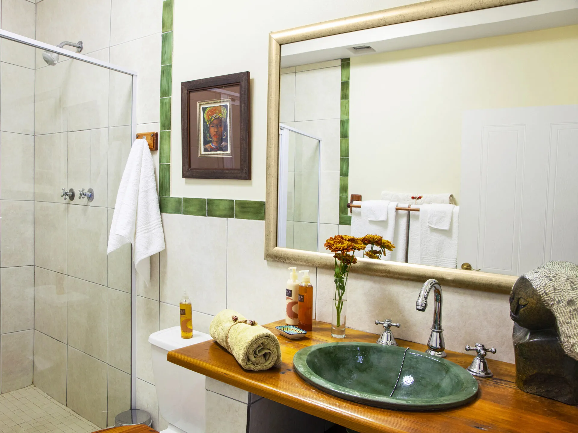 Bathroom with green sink wooden vanity mirror and shower area with towel