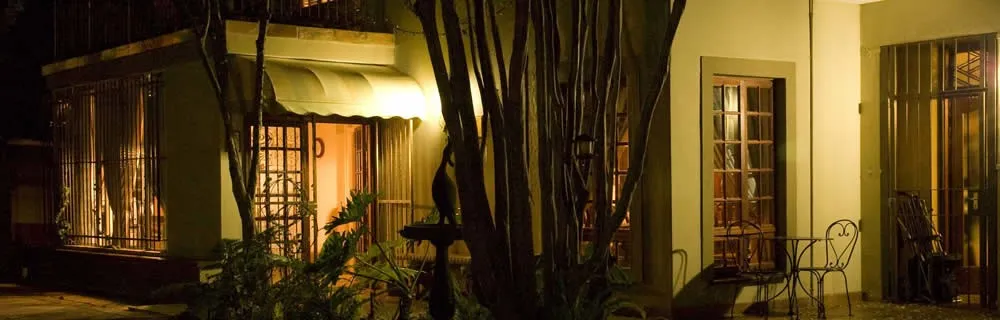 House at night with illuminated windows plants and outdoor seating