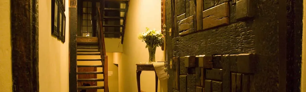 Wooden staircase in a dimly lit hallway with a floral arrangement on a table