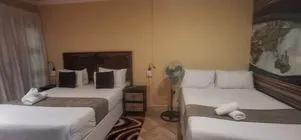 Two beds in a hotel room with towels on them and a fan